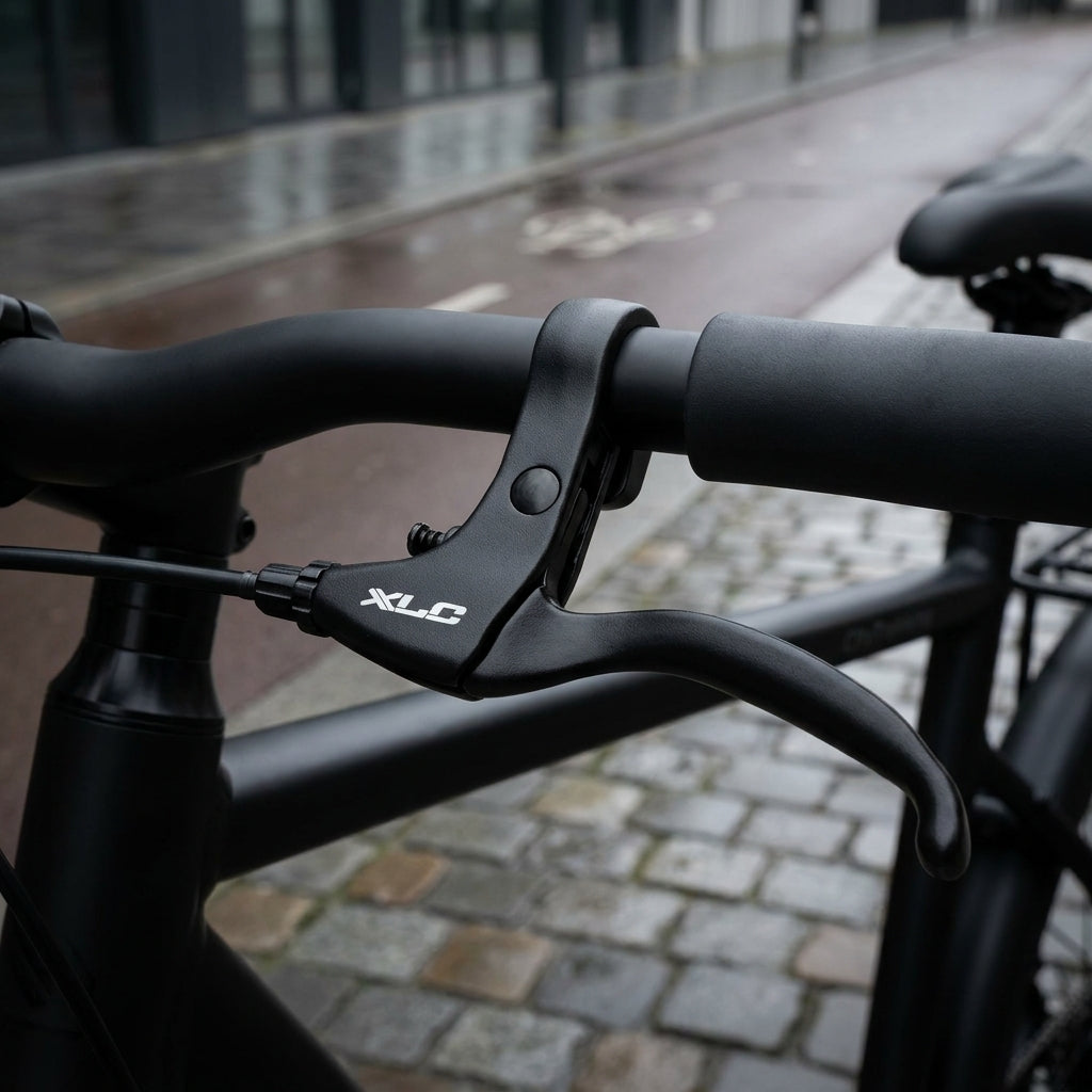 XLC Bremshebelset BL-V13 Alu schwarz für Trommelbremse am schwarzen Fahrradlenker auf nasser Straße.
