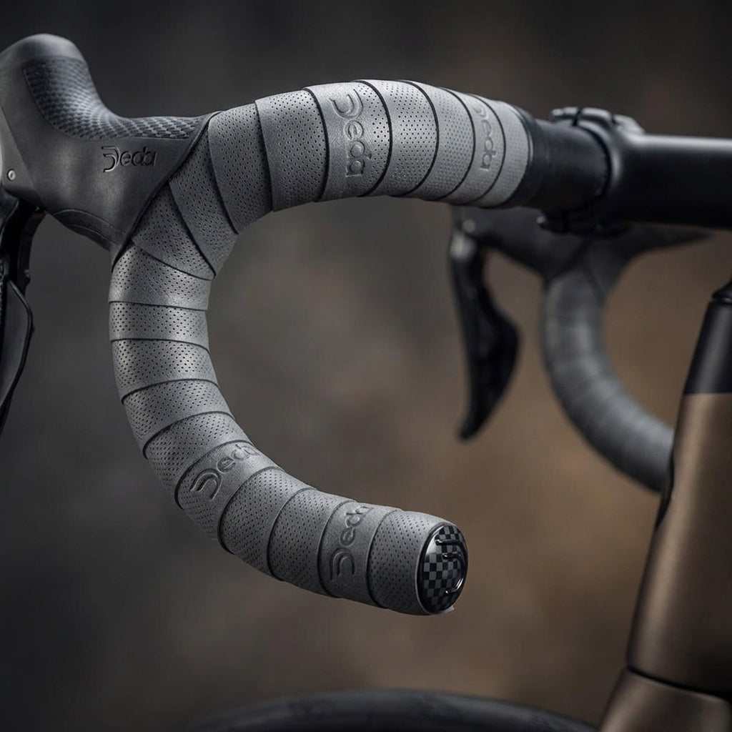 Anthrazitfarbenes Deda Lenkerband mit perforierter Oberfläche und Carbon-Lenkerstopfen am Rennradlenker.