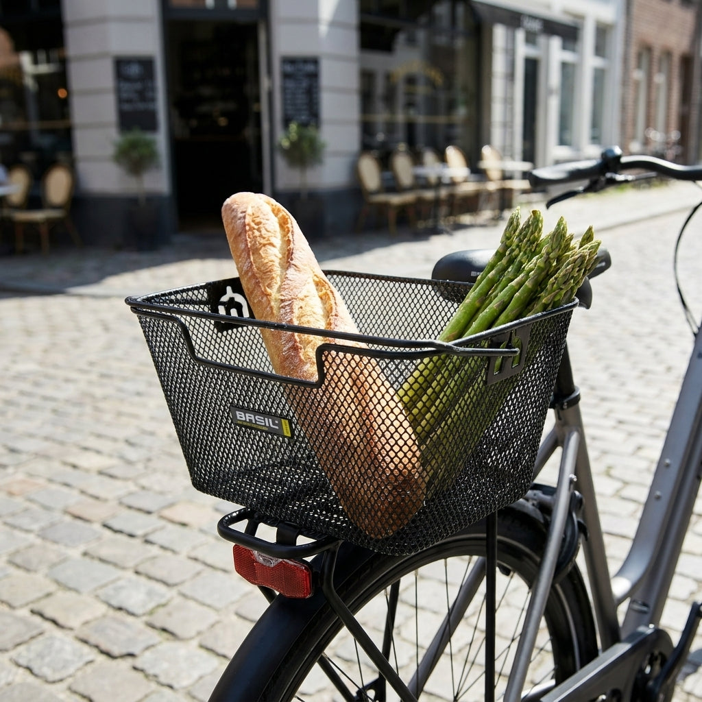 Schwarzer Basil Capri Hinterradkorb am Fahrrad mit Baguette und frischem Spargel für den Einkauf.