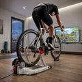 ELITE Qubo Power Smart B+ Rollentrainer: Radfahrer trainiert mit Bluetooth Heimtrainer für 20-29 Zoll vor TV.