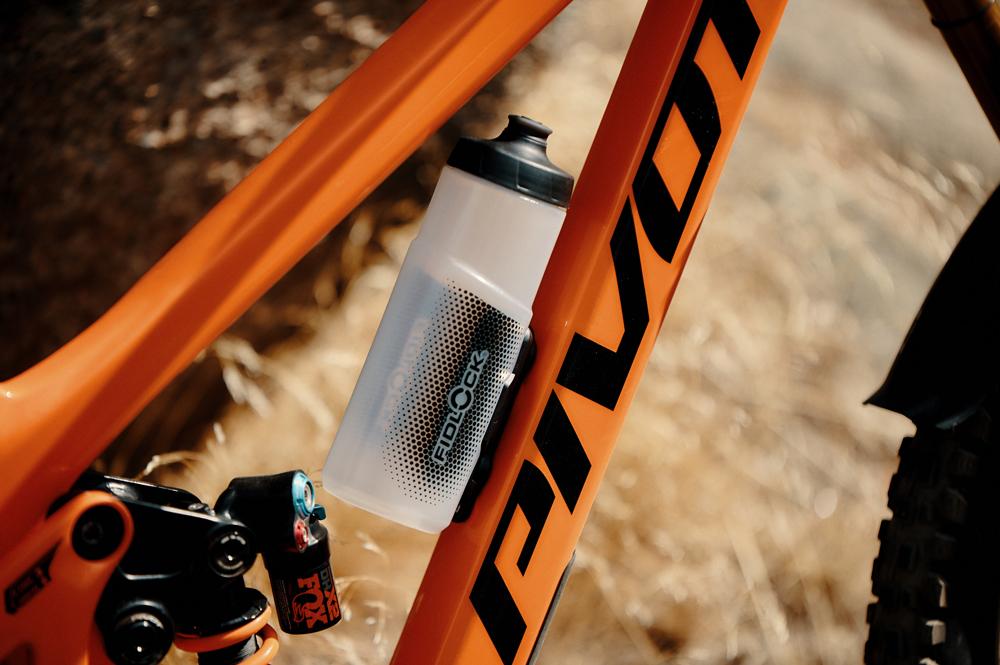 FIDLOCK TWIST Flasche 600ml sicher magnetisch am orangefarbenen Fahrradrahmen befestigt für einfaches Handling.