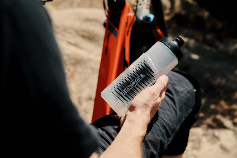 Hand hält FIDLOCK TWIST BOTTLE 600ml, magnetische Trinkflasche für sicheres & einfaches Handling am Fahrrad.