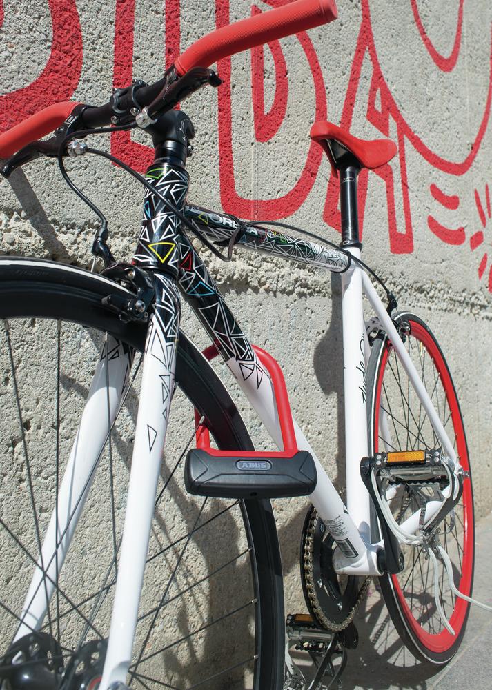 Abus Bügelschloss Granit Plus 640 rot, befestigt an einem weißen Fahrrad mit roten Akzenten.