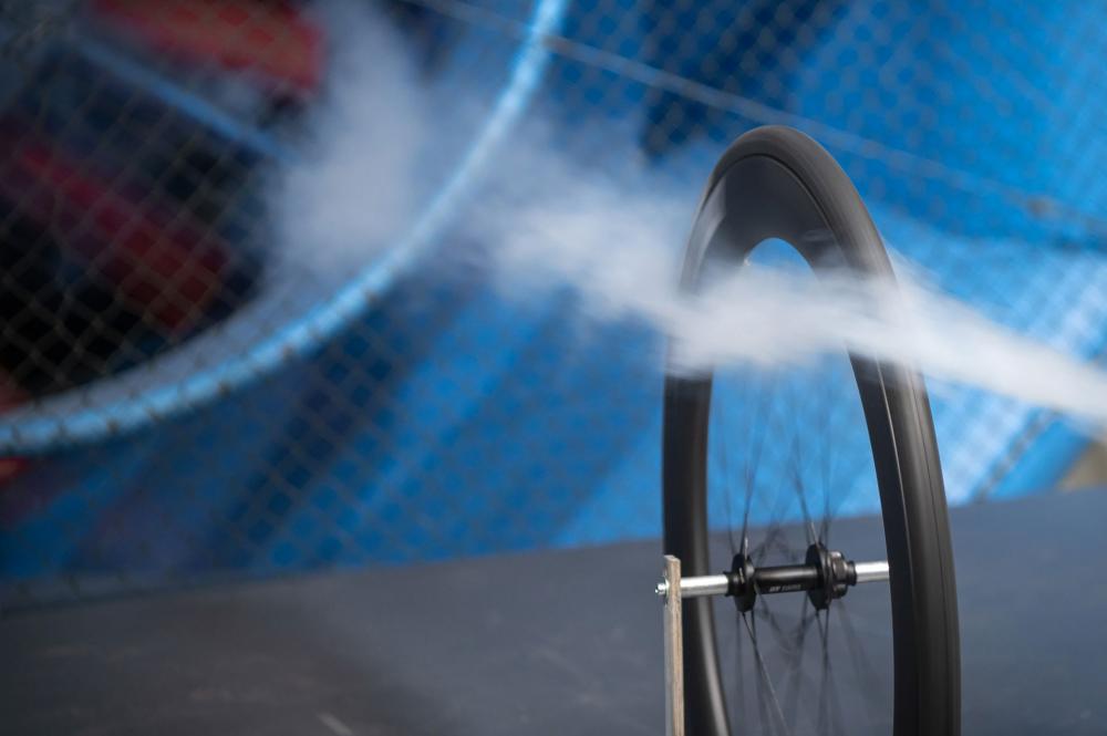 Schwarzes aero-optimiertes DT Swiss ERC 1100 Dicut Carbon-Laufrad im Windkanal mit Luftstrom.