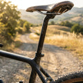 Ergotec Viper Level 5 Patentsattelstütze am Gravelbike mit Ledersattel auf sonnigem Schotterweg.