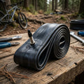Impac Fahrradschlauch 29 Zoll mit Sclaverand-Ventil auf Holztisch, Mountainbike im Wald.