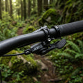 SHIMANO DEORE XT SL-M8100 Links I-Spec EV 2-fach Schalthebel auf Carbon-Mountainbike-Lenker im Wald.