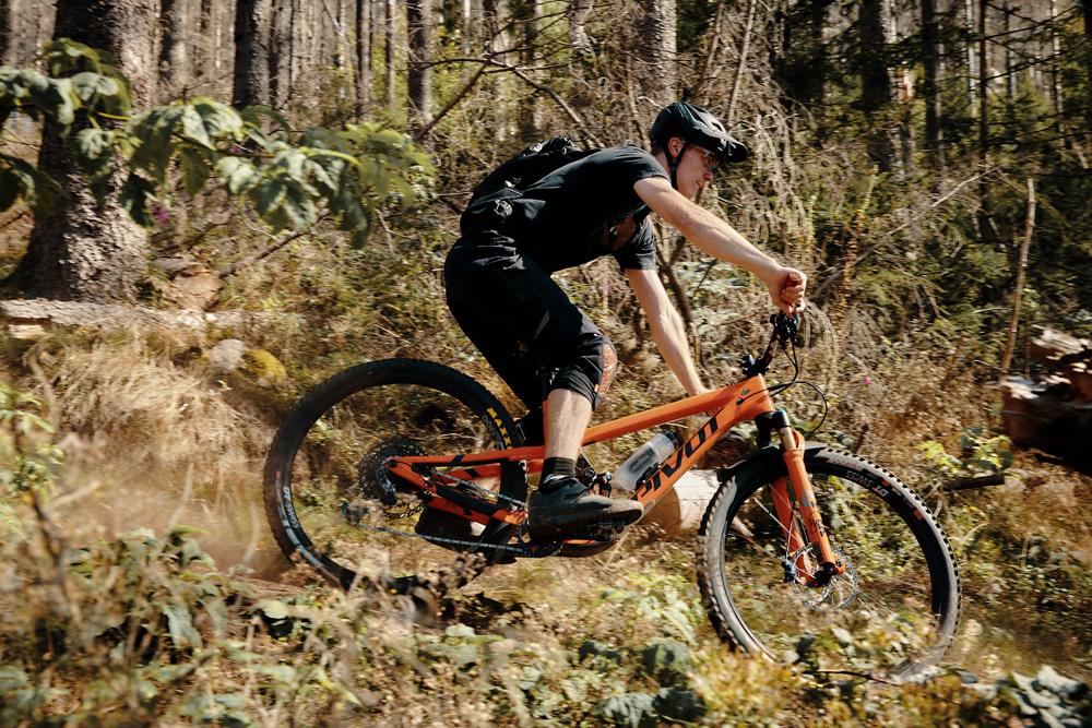 Mountainbiker fährt mit FIDLOCK TWIST BOTTLE 600ml Magnet-Flaschenhalterung am Fahrrad durch den Wald.