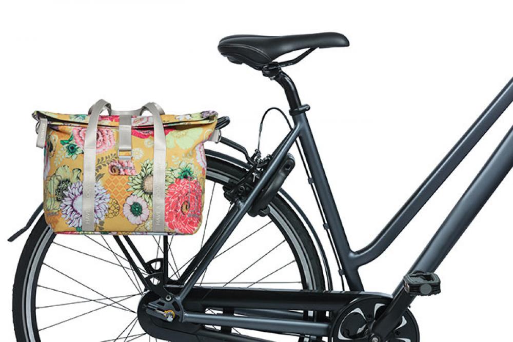 Basil Schultertasche Bloom Field honey yellow mit Blumenmuster am Fahrrad-Gepäckträger befestigt.