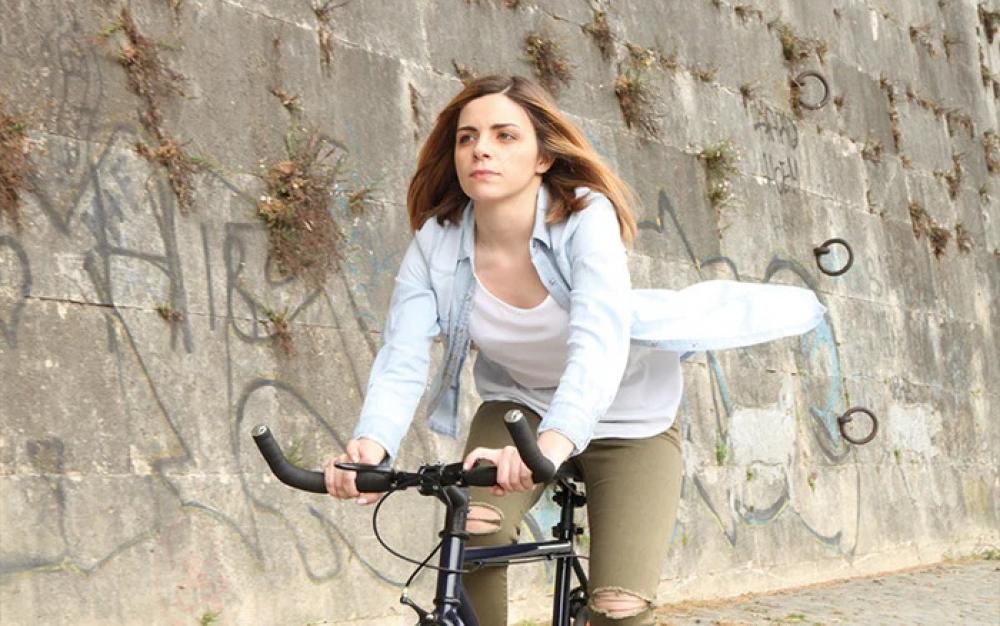 Sportliche Frau fährt Fahrrad mit komfortablem schwarzem Selle Royal Freeway Fit Classic Sattel vor Betonwand.