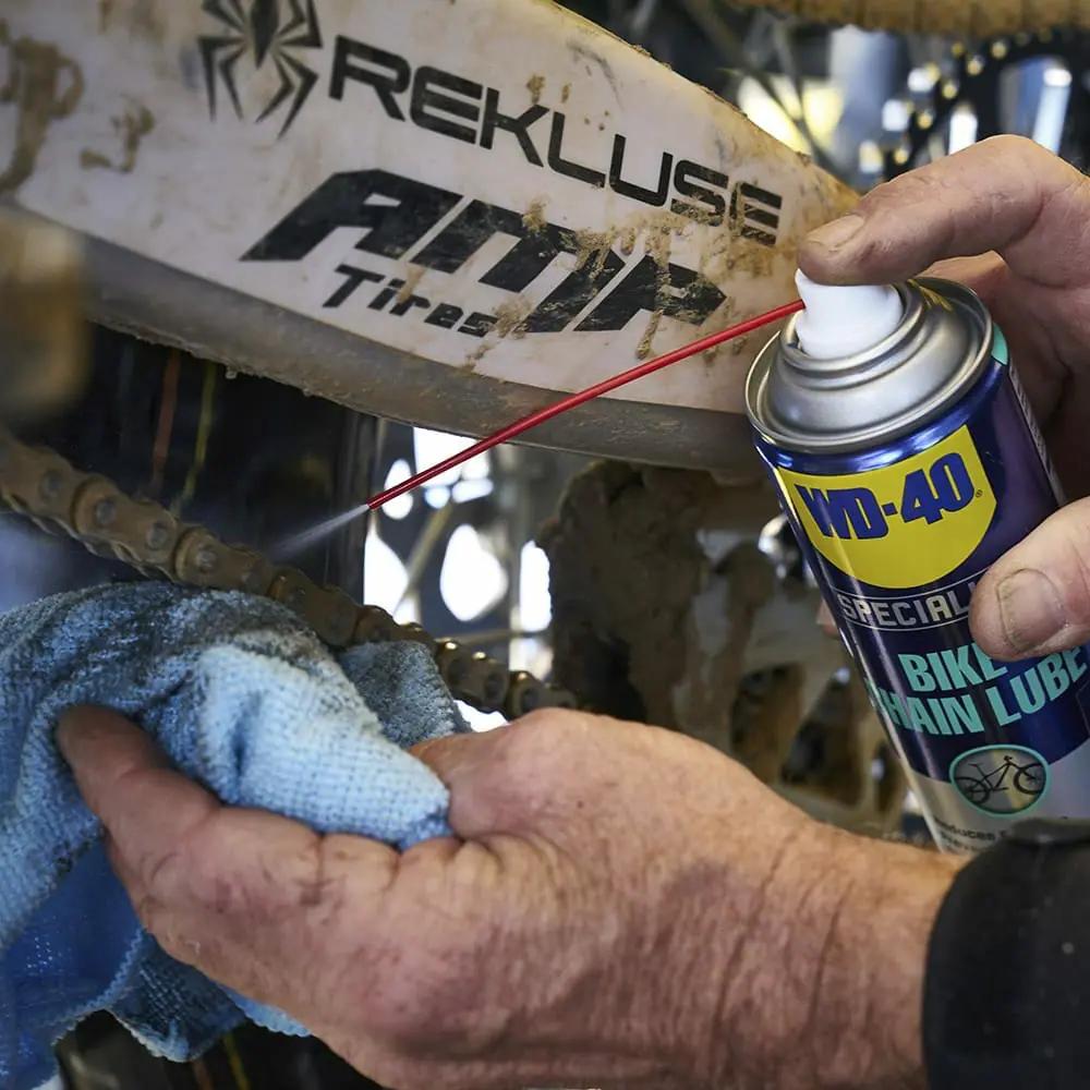 Anwendung von WD-40 Kettenspray auf einer Fahrradkette für Allwetter-Schmierung und Korrosionsschutz.