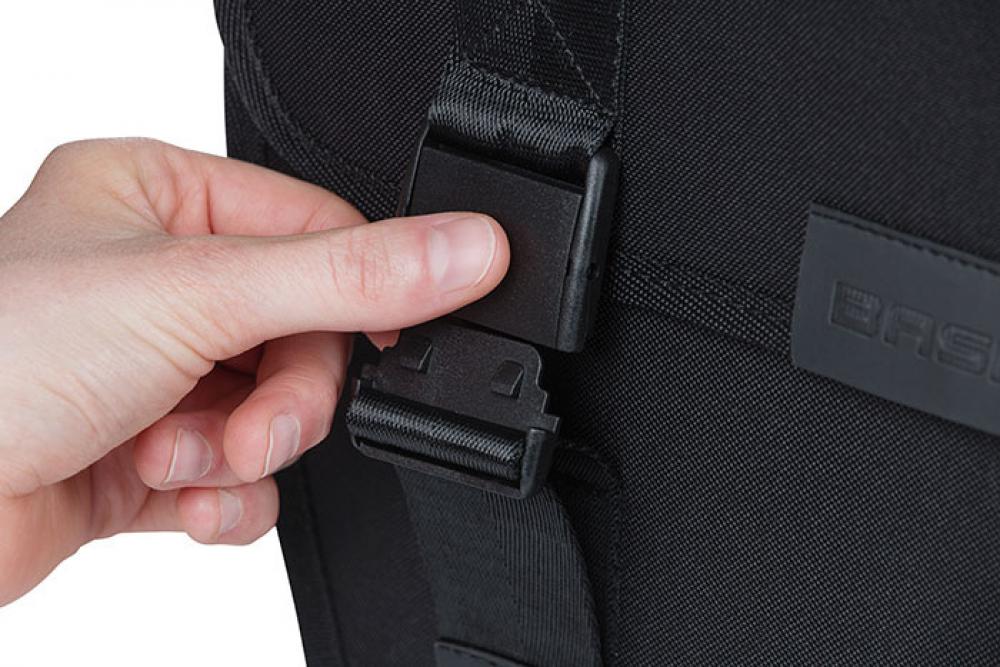 Hand öffnet schwarze Schnalle an schwarzer Basil Doppelpacktasche Tour XL, 35l.
